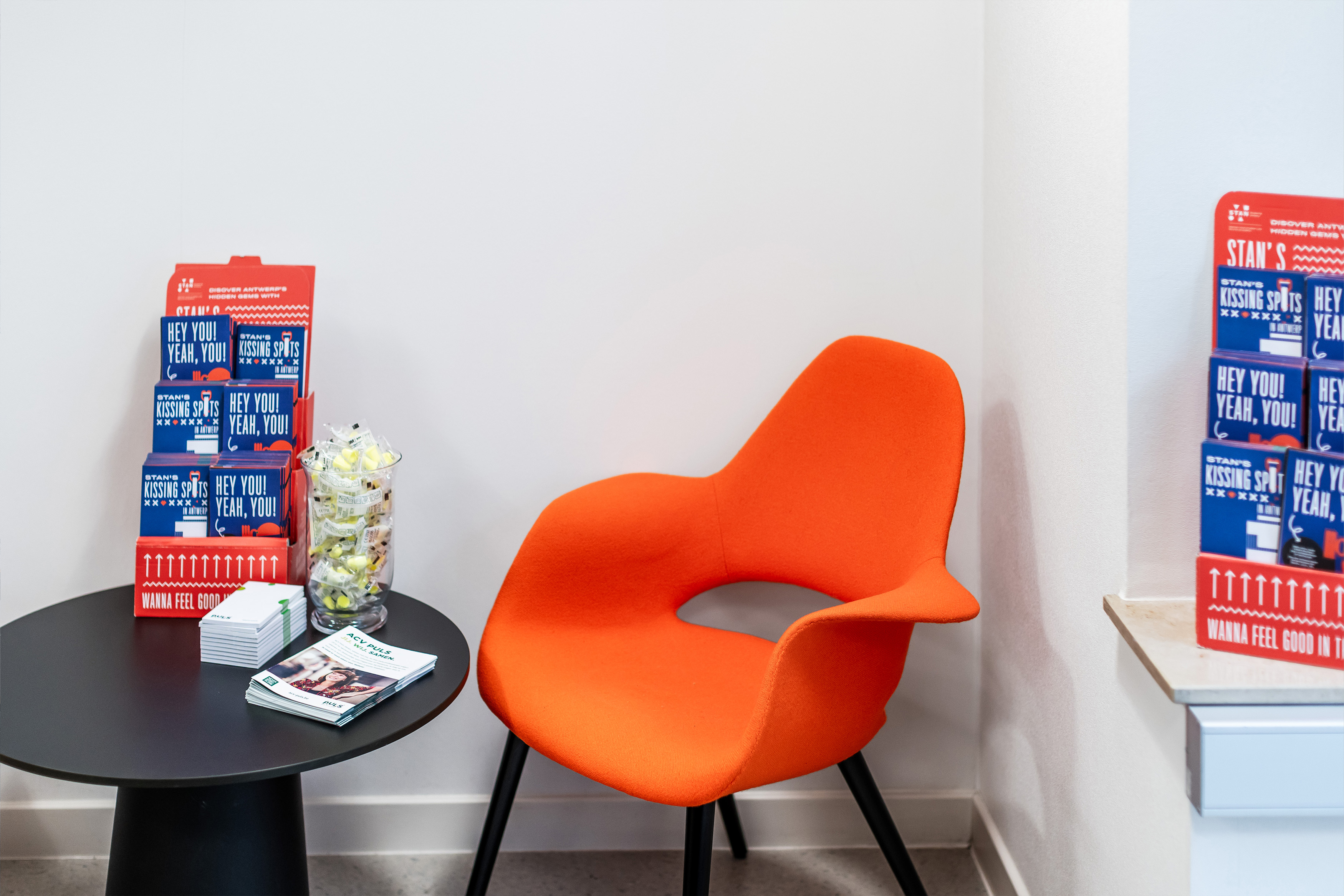 Een leeshoek met oranje stoel met tafeltje ernaast waarop de STAN Student Map's staan en folders van ACV Puls