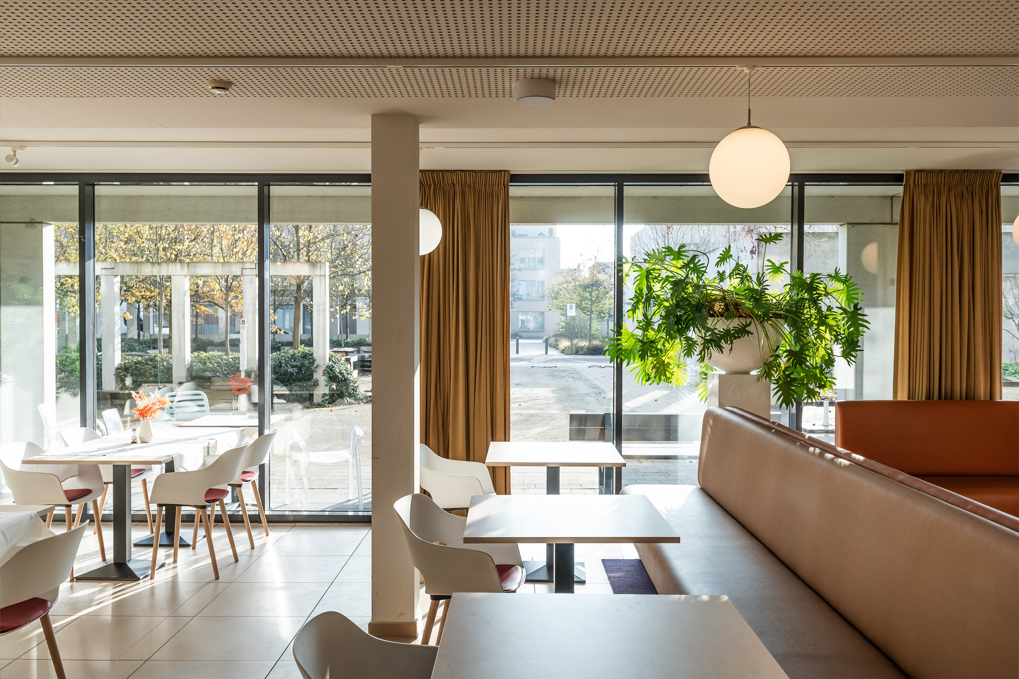 Zicht op de zonovergoten studeerplek met tafels, stoelen en comfortabele bankjes en salonnetjes