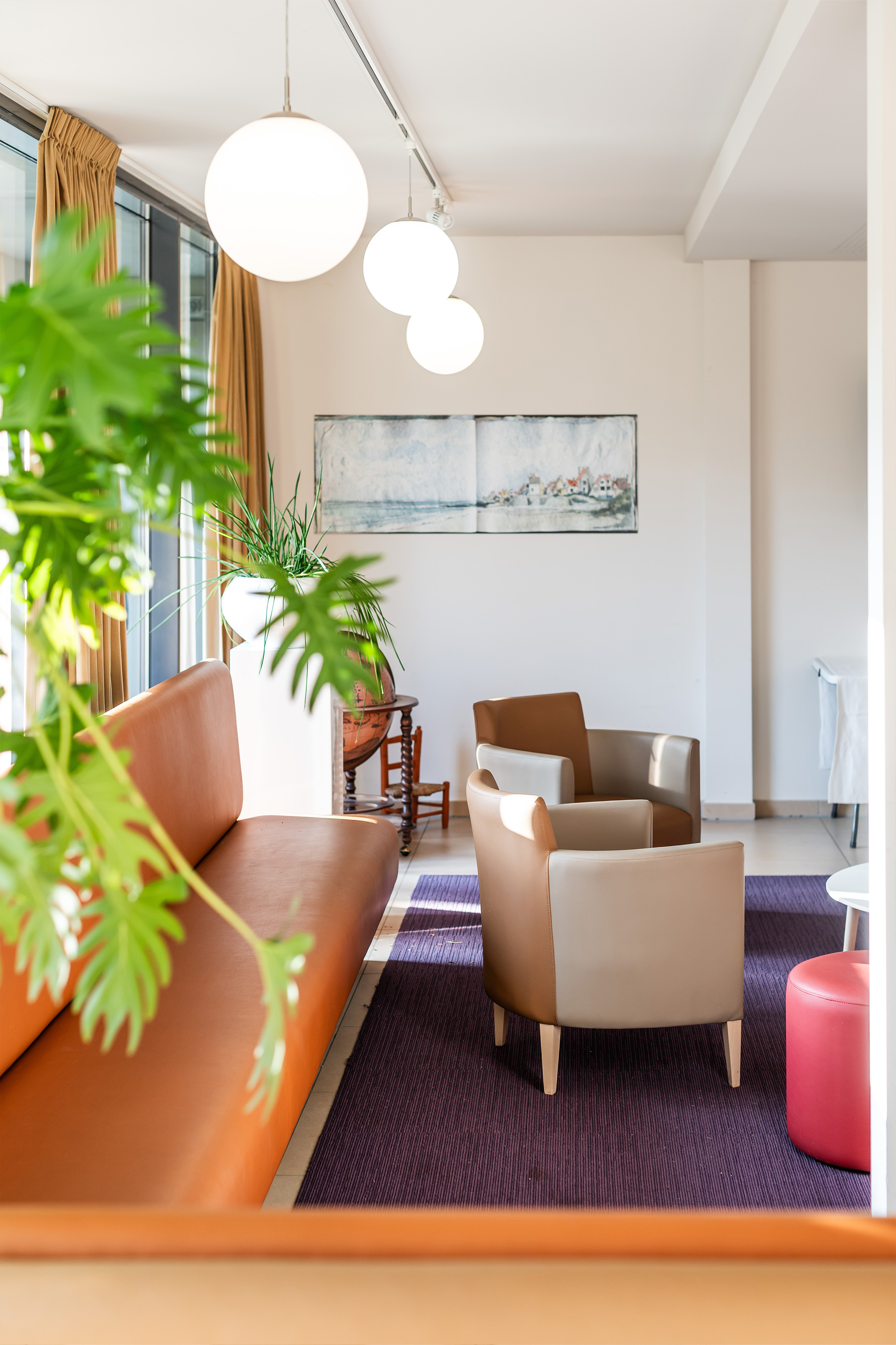 Een zonovergoten salon met bank, 2 losse zeteltjes en poef