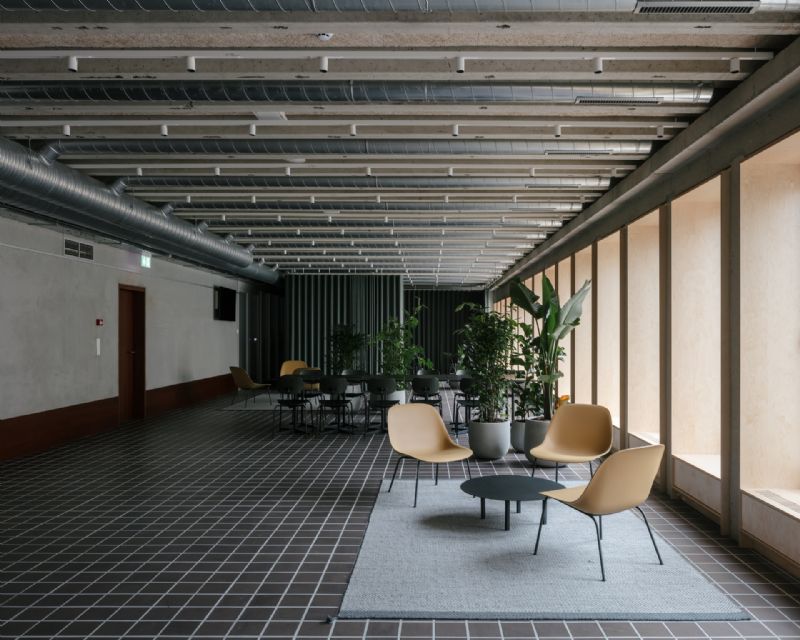 Binnenaanzicht van een kantoorgebouw waar enkele stoelen rond een ronde tafel staan opgesteld en planten op de achtergrond