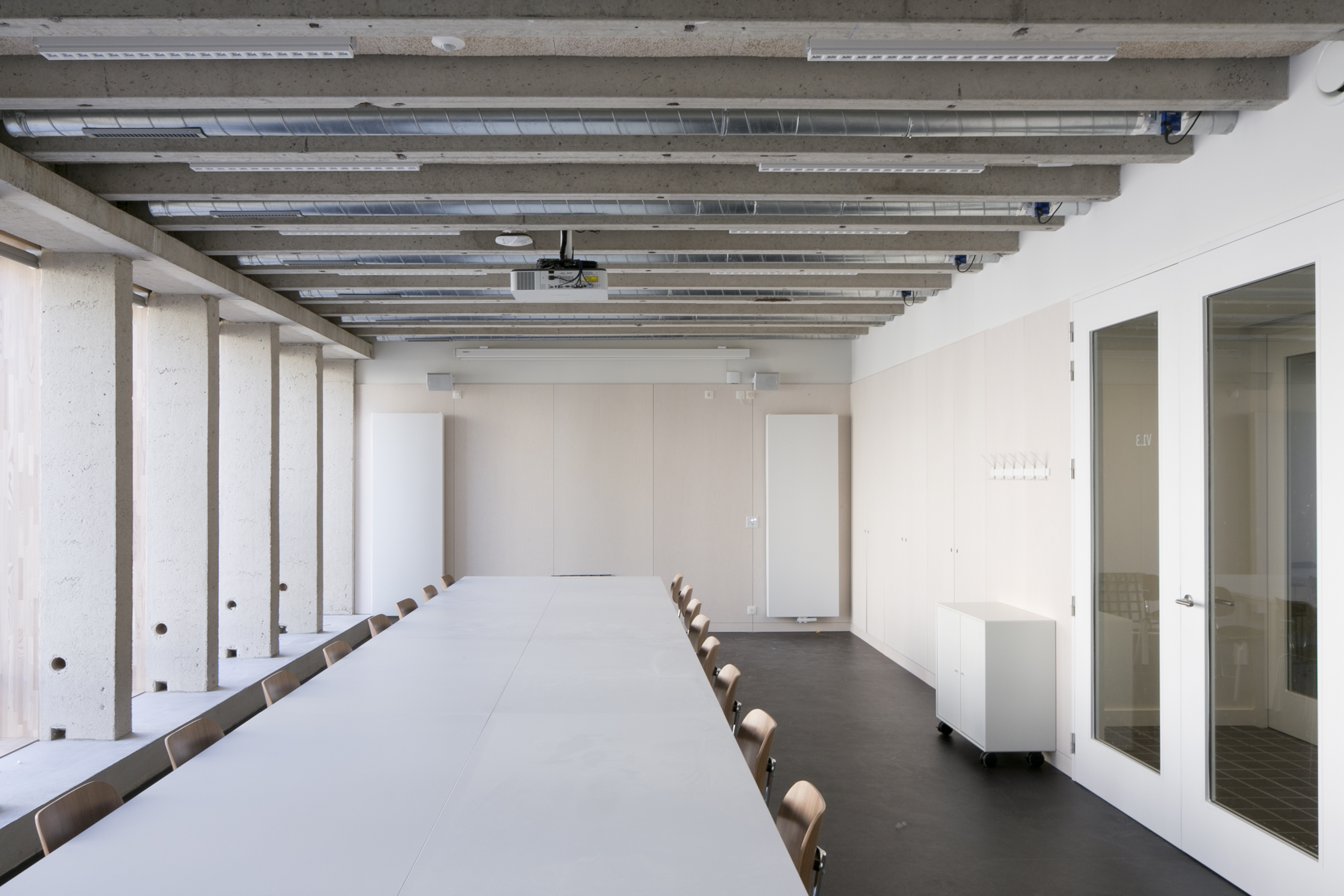 Binnenzicht op een witte studeerlocatie bij De Pit waar een lange tafel met stoelen staat opgesteld