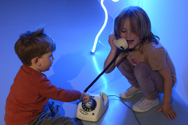 twee kinderen in het museum spelend met een oude telefoon