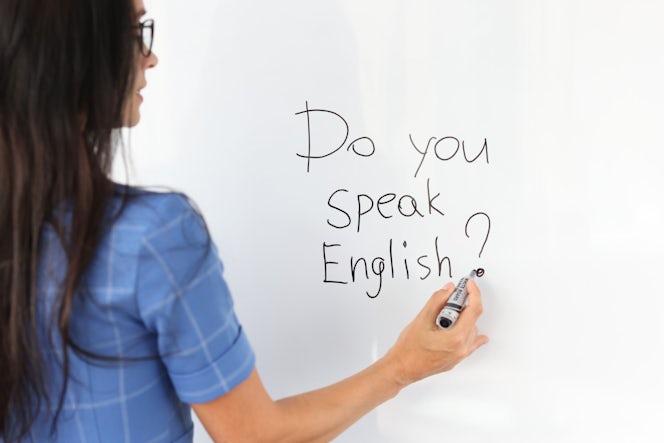 Een lesgever Engels schrijf op het whiteboard de tekst: do you speak English