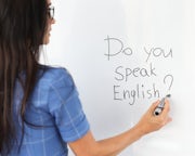 Een lesgever Engels schrijf op het whiteboard de tekst: do you speak English