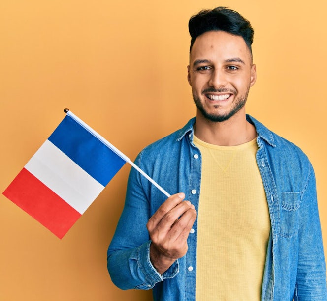 Jonge Arabische man houdt de Franse vlag vast op een effen achtergrond