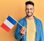 Jonge Arabische man houdt de Franse vlag vast op een effen achtergrond