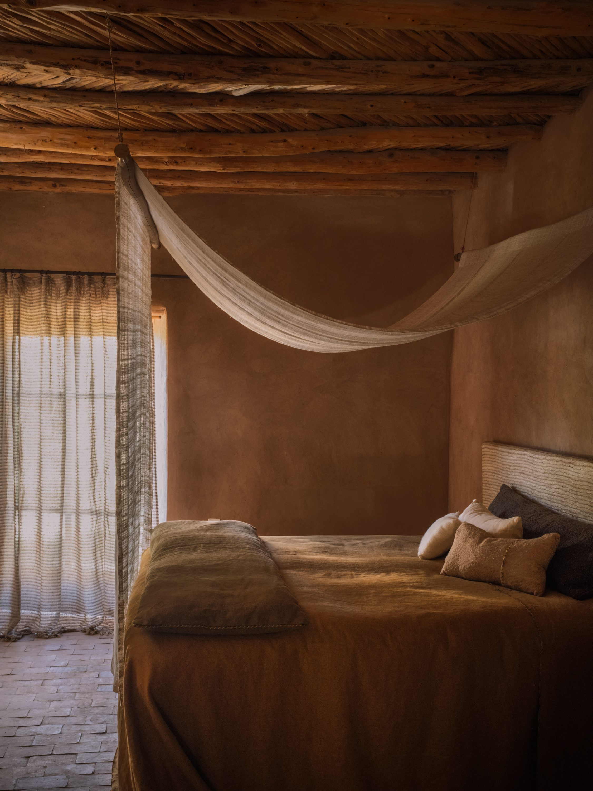 Bedsheet DHARTI YP26010 Cushions MAKI YP26001, ORION YP26007, DHARTI YP26005, SHIBUI YP26005, Fouton GRAVITAS YP26013, Canopy JALIKA YP26001, Curtain BAGODAL YP26001 photographed in Berber Lodge for the Azimuth 2026 fabric collection by Designs of the Time