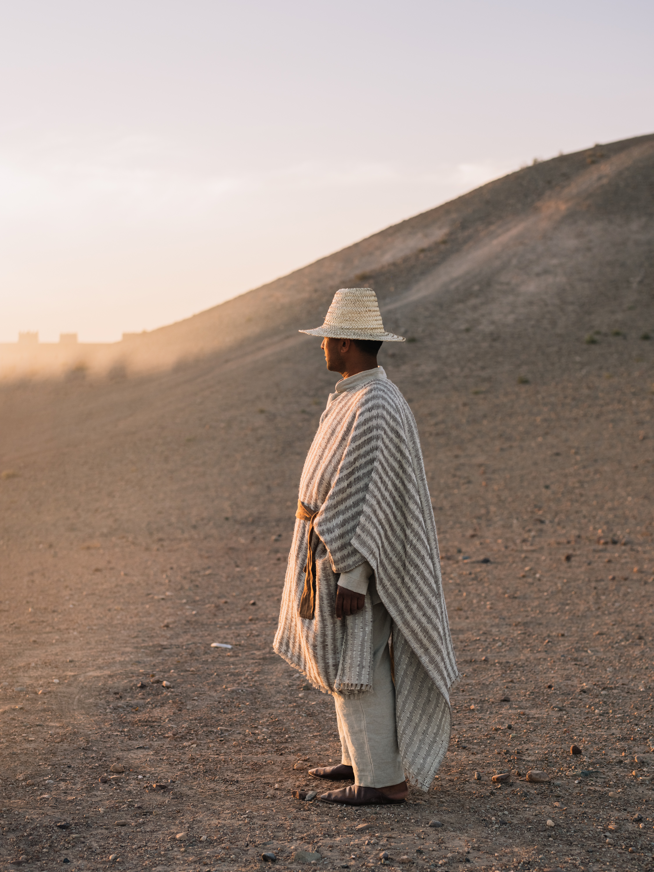 Man wearing a cape made of TARANGA YP26001 fabric photographed in the Moroccan desert for the Azimuth 2026 fabric collection by Designs of the Time