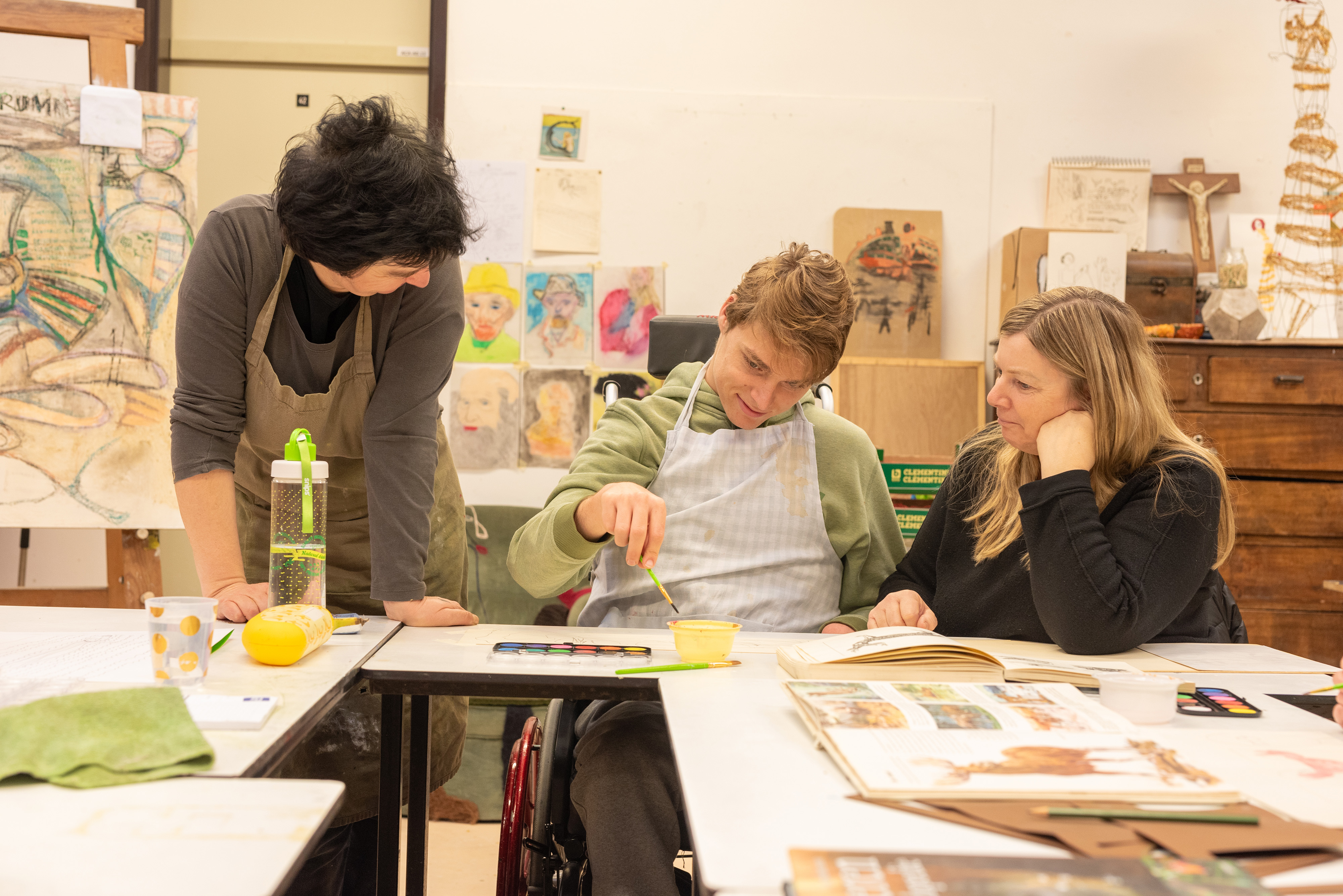 Een jonge man schildert en krijgt begeleiding