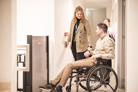 Medewerker hotel O'mer assisteert man met rolstoel