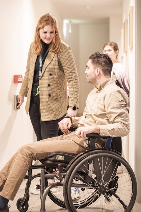 Medewerker hotel O'mer assisteert man met rolstoel