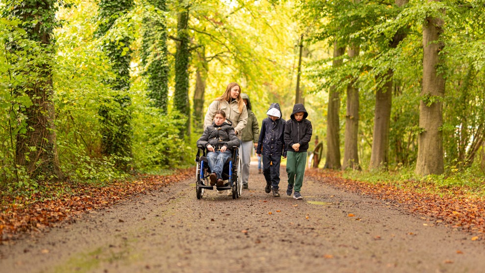 Medewerker en groep kinderen op uitstap in het bos in de herfst