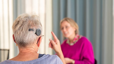 Vrouw met hoorimplantaat spreekt in gebarentaal met een medewerker