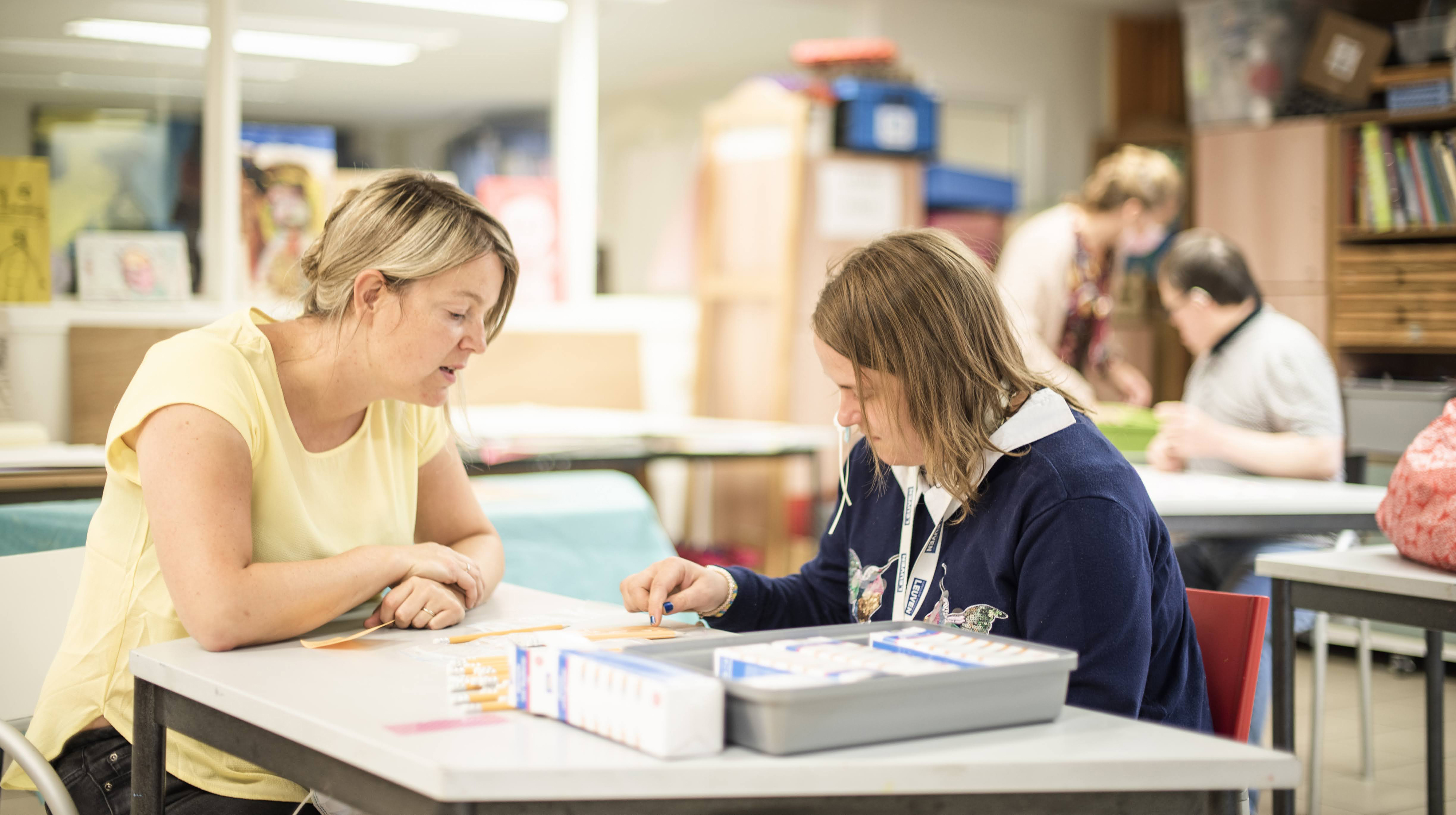 Twee mensen zitten aan een tafel en doen samen een sorteerwerk