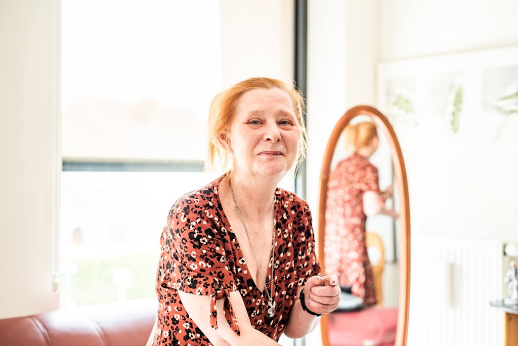 Een vrouw staat voor een spiegel en lacht naar de camera