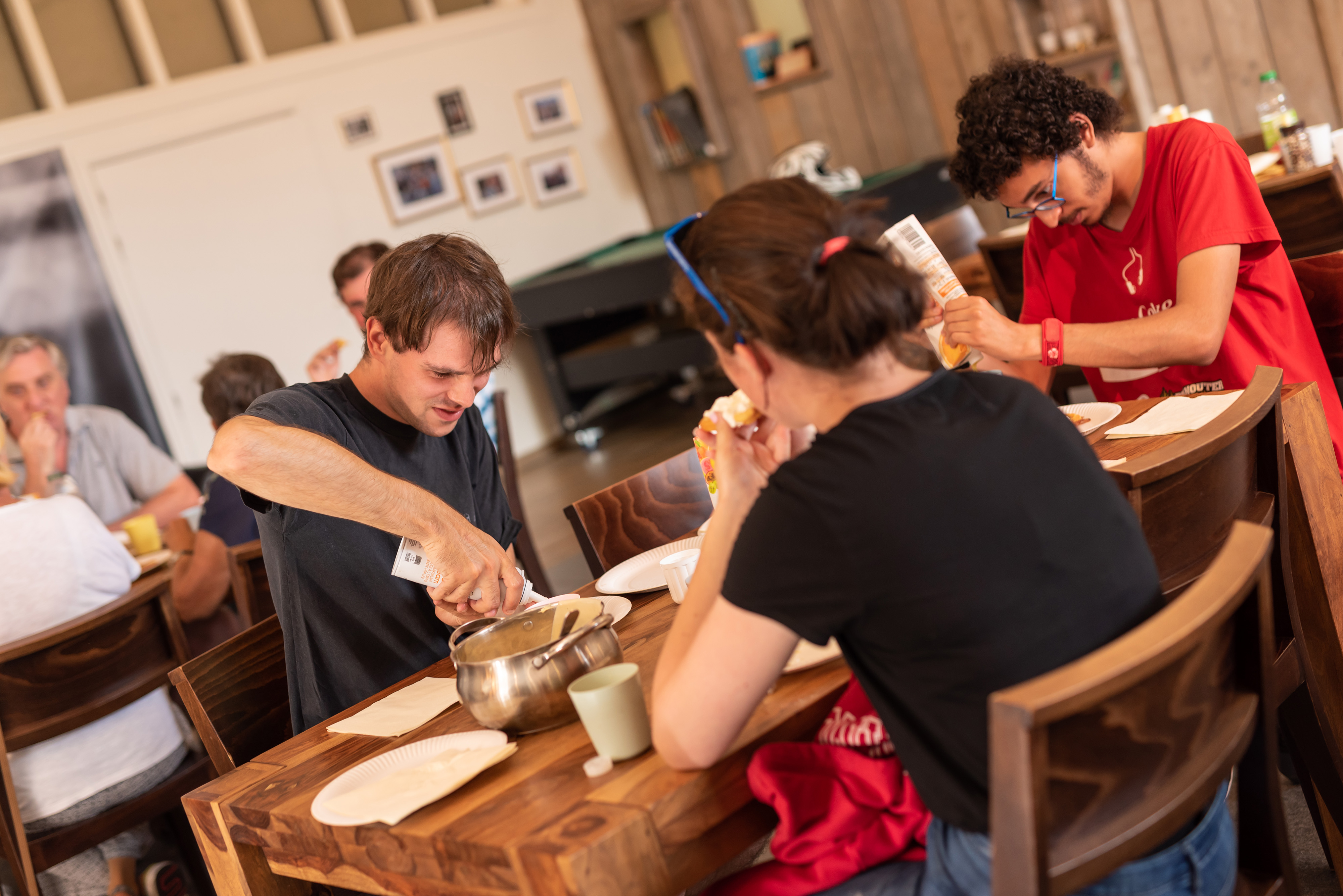 Een groepje mensen zit samen aan de tafel wafels te eten
