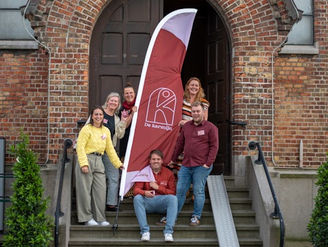 collega's van Oranje staan voor kapel met vlag van logo de Karmijn