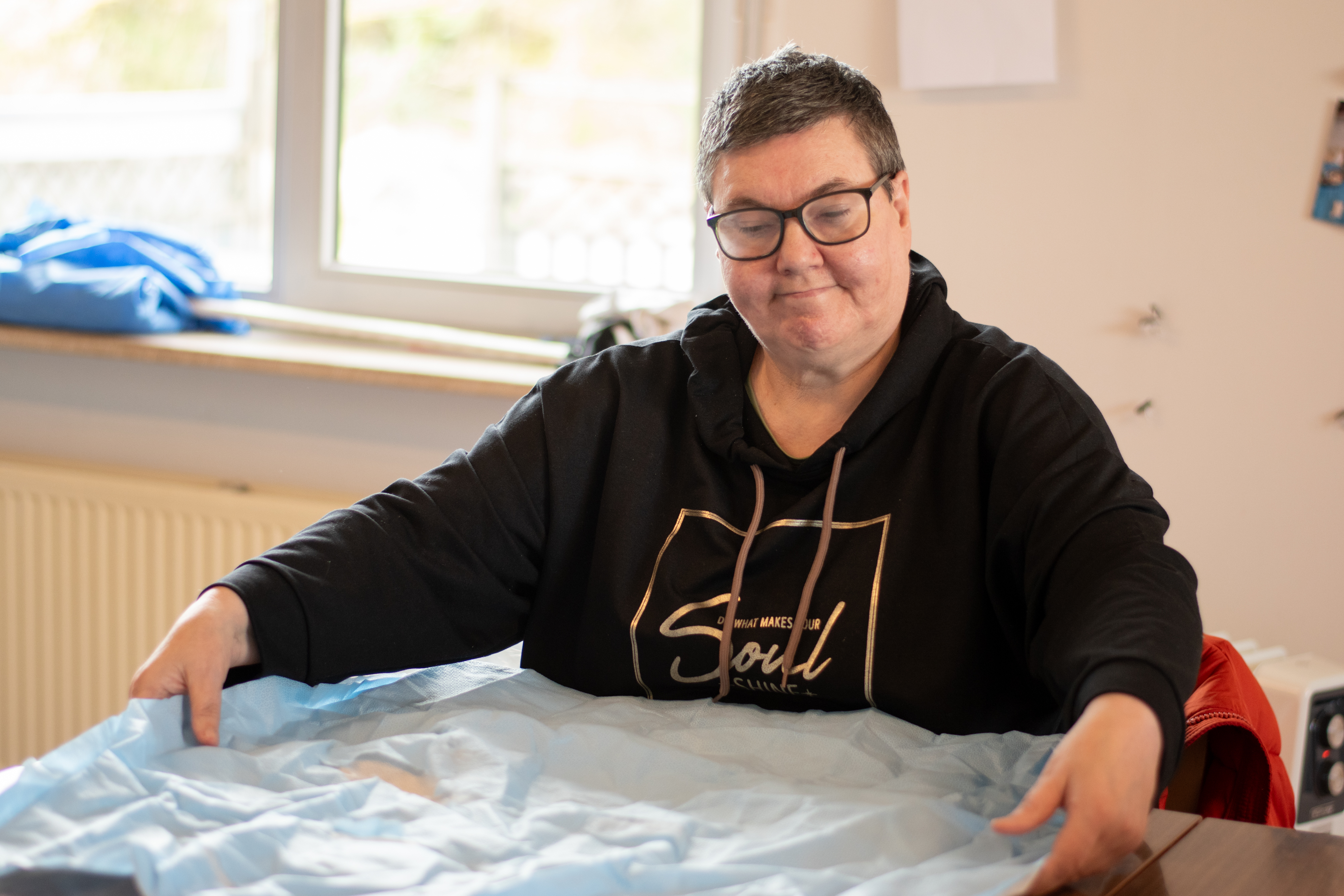 Vrouw vouwt sterilisatiedoeken dicht en lacht naar de camera