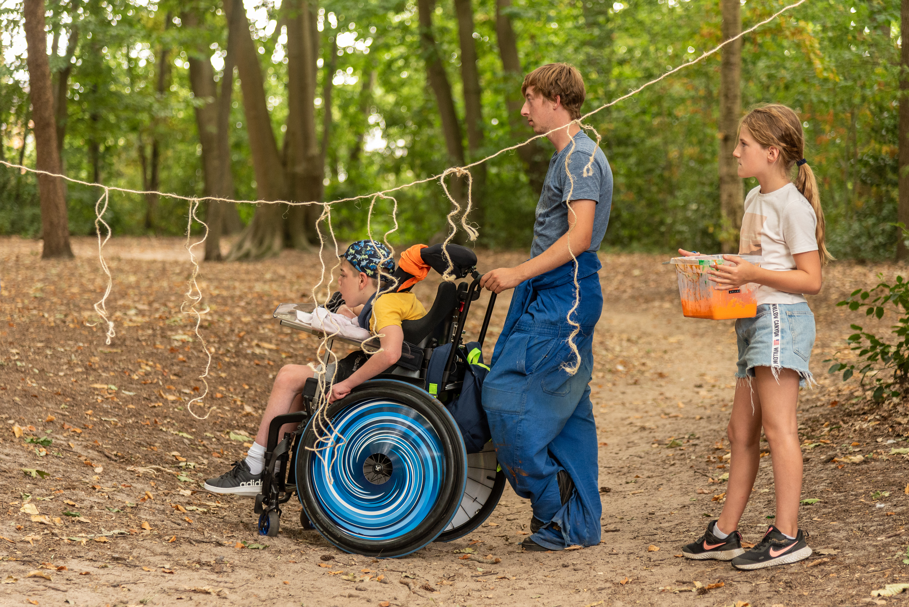 Jongere begeleidt jongere in rolstoel op de speelpleinwerking