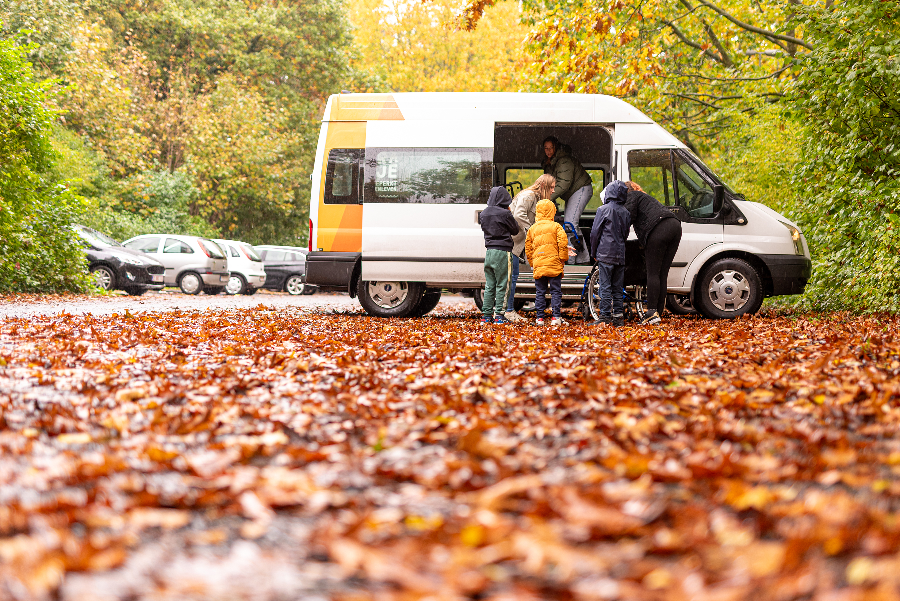 Kinderen stappen op een herfstige dag uit een bus bij een speelpleinactiviteit.