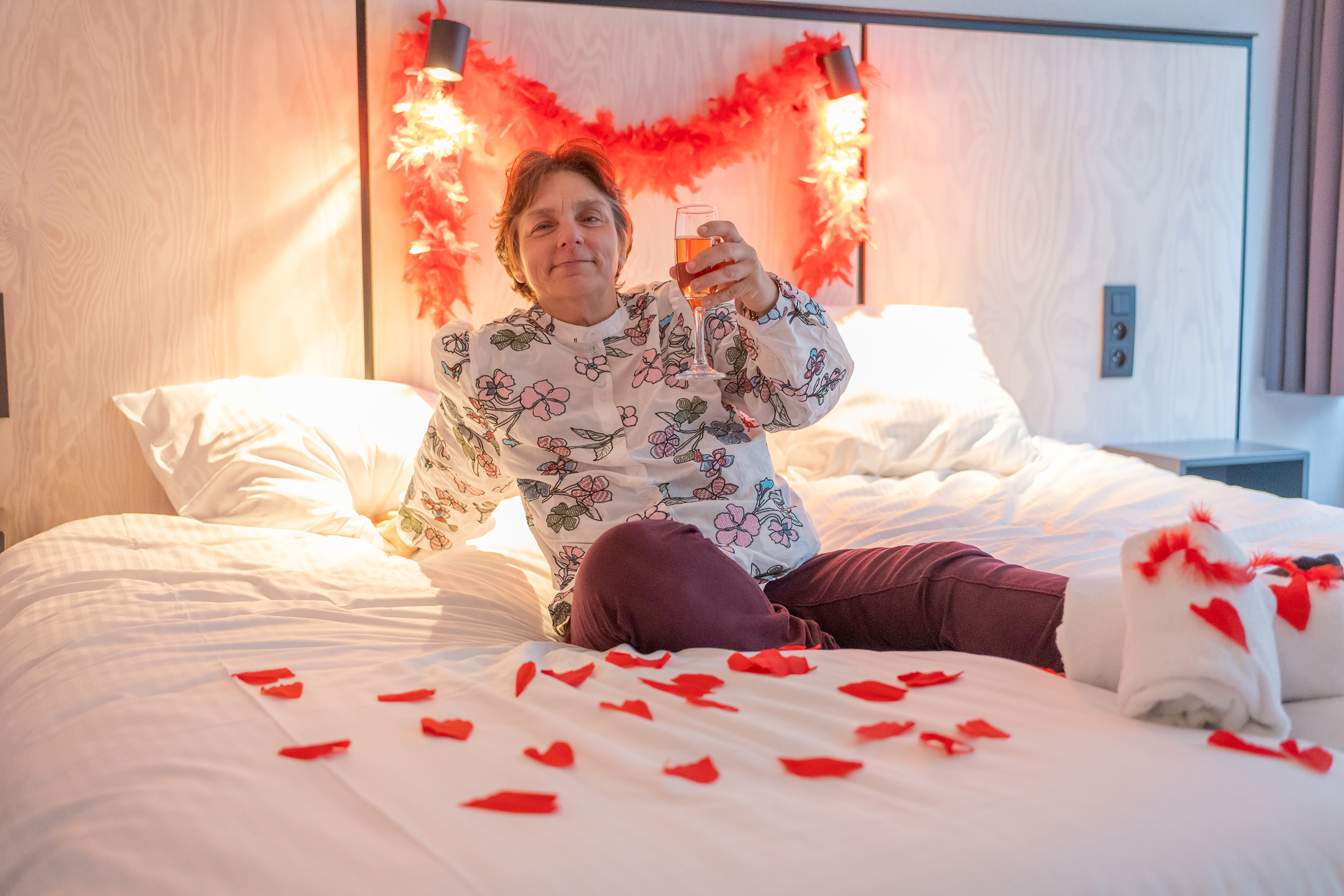 Vrouw in hotelkamer viert met een glaasje bubbels