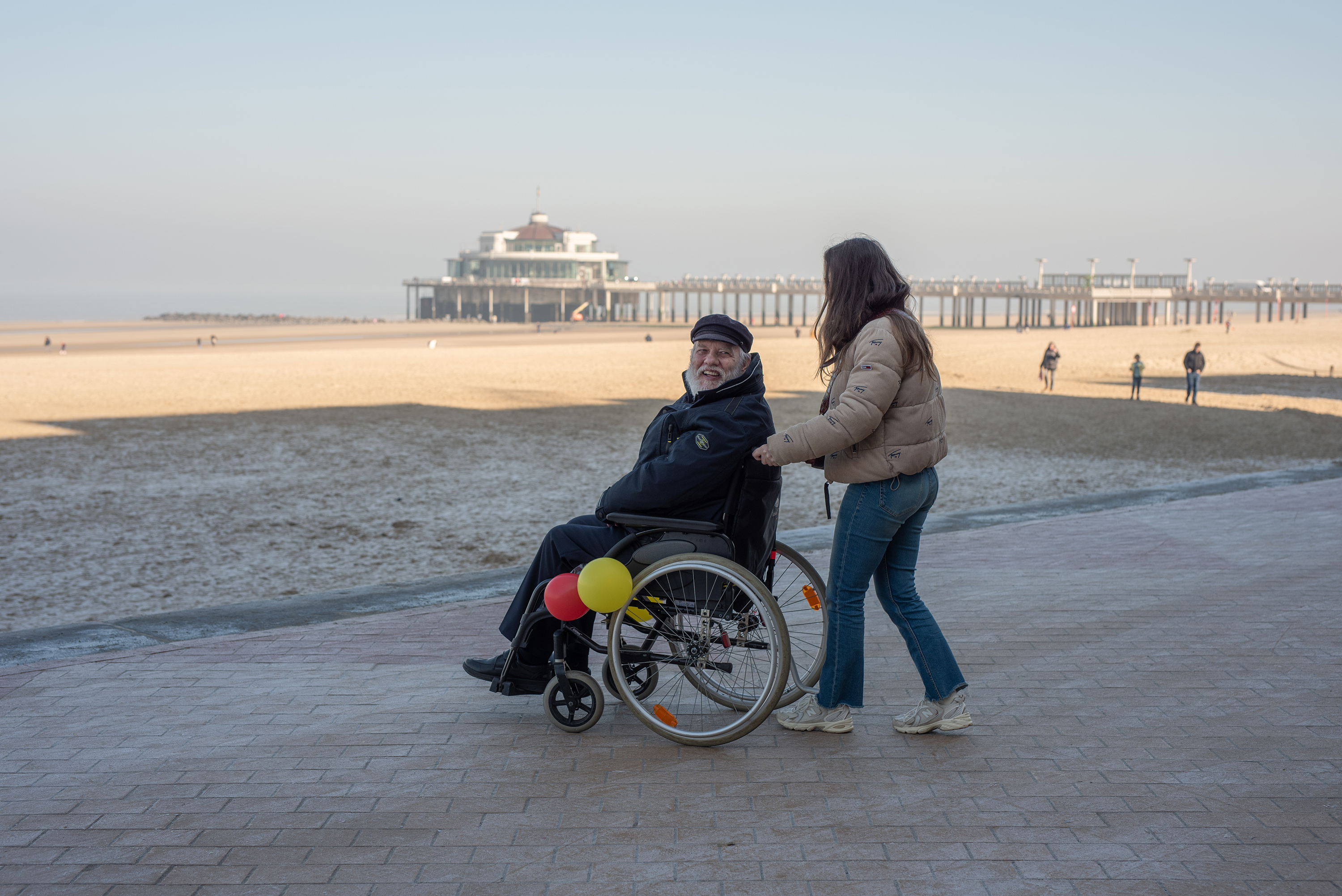 Hotelgast in rolstoel op wandel met begeleider