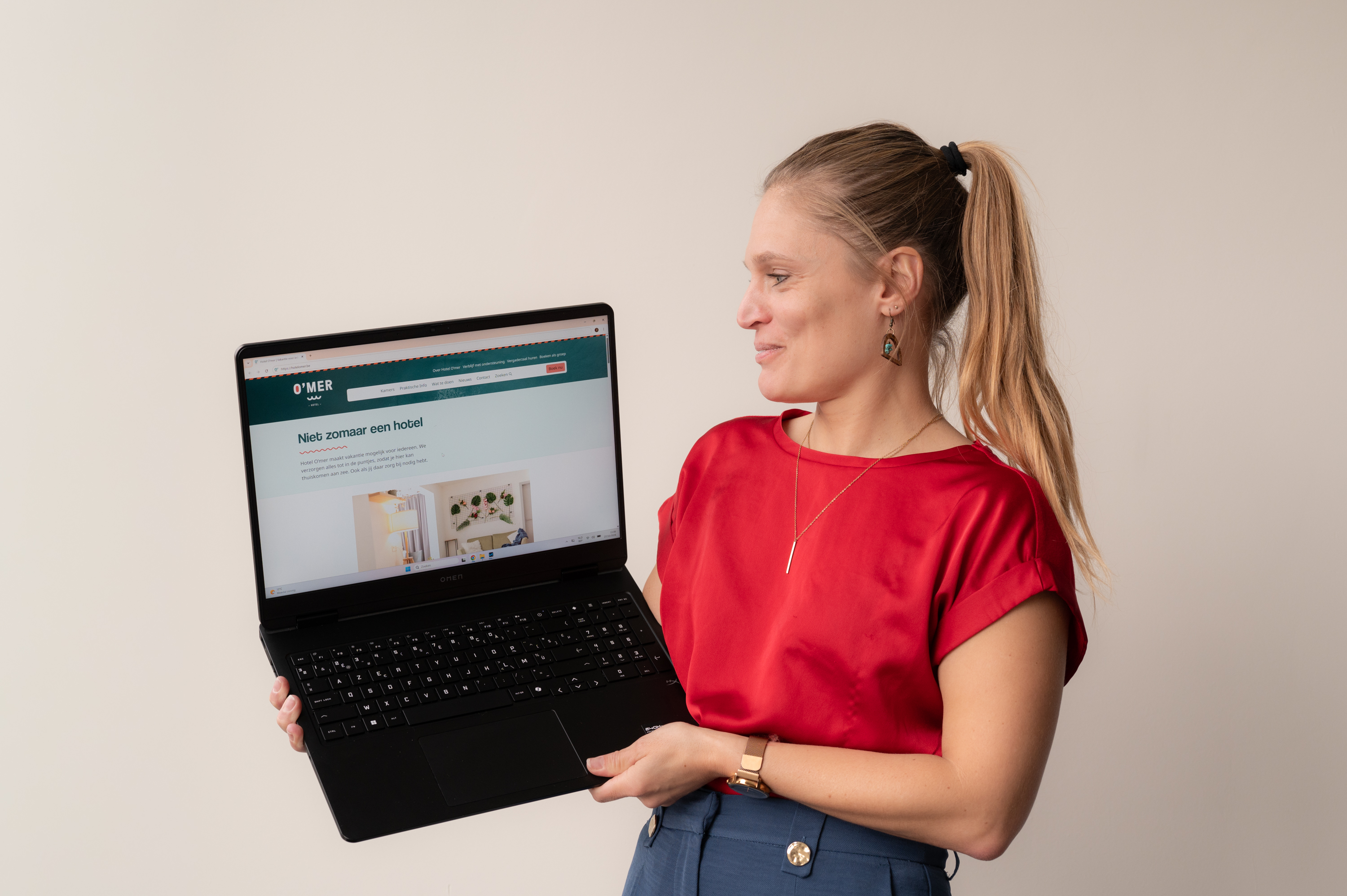 Vrouw toont laptop met nieuwe website hotel O'mer op het scherm