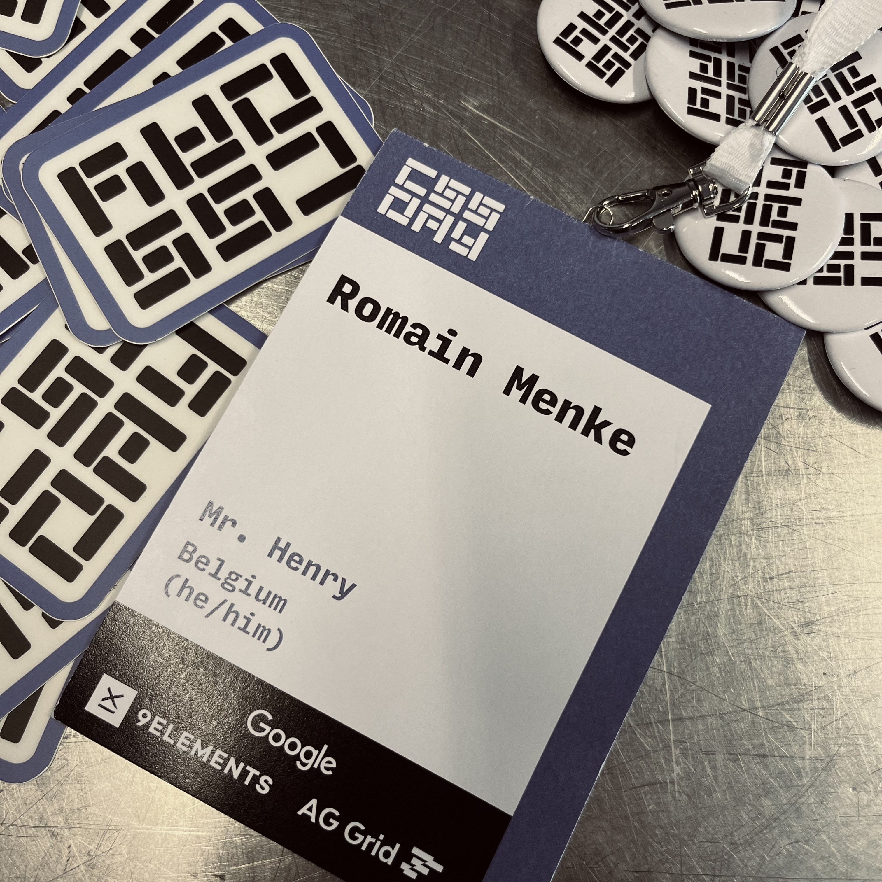 Romain's lanyard for the CSS Day 2026 conference, surrounded by all the CSS Day stickers and pins.